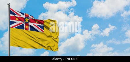 Niue Flagge im Wind gegen Weiße bewölkt blauer Himmel. Diplomatie Konzept, internationale Beziehungen. Stockfoto