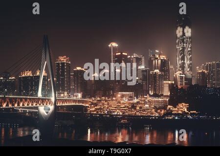 Qiansimen Brücke mit Hongyadong Shopping Complex und Stadt städtische Architektur bei Nacht in Chongqing, China. Stockfoto