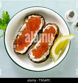 Frisches Brot Sandwich mit rotem Kaviar und weichem Käse auf einem Teller. klassische Kombination der Zutaten. Snack auf dem Tisch Stockfoto