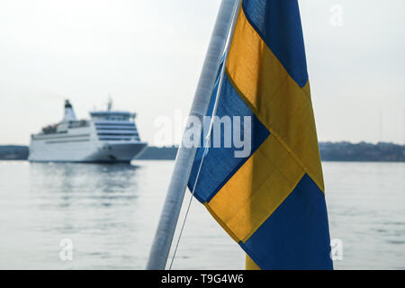 Die schwedische Flagge hängen auf der Fähre in Stockholm mit einem großen ozeanischen Bootsfahrt im Hintergrund. Stockfoto