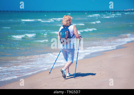 Eine ältere Frau üben Nordic Walking am Strand Stockfoto