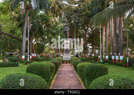 Ein malerischer Steinweg, gesäumt von gepflegten Topiärsträuchern, der zur Bal-Gangadhar-Tilak-Statue im Nana-Nani-Park in Mumbai, Indien, führt. Stockfoto
