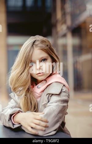 Sehr schöne kleine Mädchen mit langen blonden Haaren und blauen Augen an einem Tisch sitzen außerhalb Stockfoto