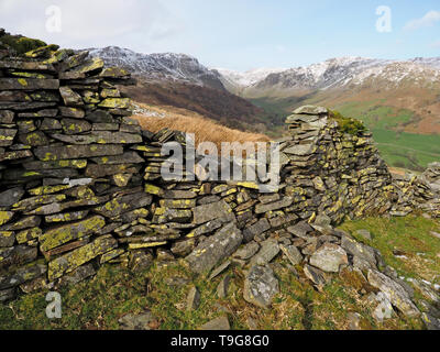 Landschaft in langen Sleddale Cumbria, England, UK mit gebrochenen Trockenmauer in Flechten bedeckt, über dem Tal und Schnee auf die fernen Hügel Stockfoto