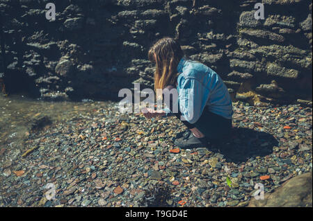 Eine junge Frau ist das Sammeln von Sachen am Strand an einem sonnigen Sommertag Stockfoto