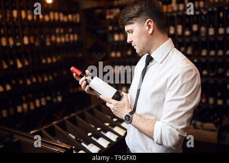 Schönen eleganten Mann Kunden dabei, das genaue Wein, der am besten Ihren Anforderungen entspricht. nach oben Seitenansicht schließen Foto zu entscheiden. Stockfoto