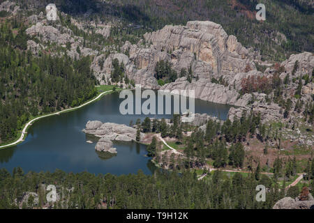 Ein Luftbild von Sylvan Lake in South Dakota an einem sonnigen Tag mit großen Felsformationen und hohen Bäumen umgeben. Stockfoto