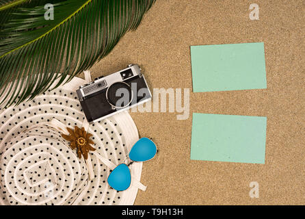 Blick von oben auf Palmblättern, retro Foto Kamera und Sonnenbrille am Strand sand Hintergrund. Flach. Travel Concept, leeren Raum für Text Stockfoto