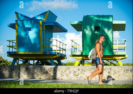 MIAMI - Juli 2017: Junges Paar Spaziergänge entlang der Promenade von Miami Beach vor Leuchtendbunten neu errichtete rettungstürme am South Beach. Stockfoto