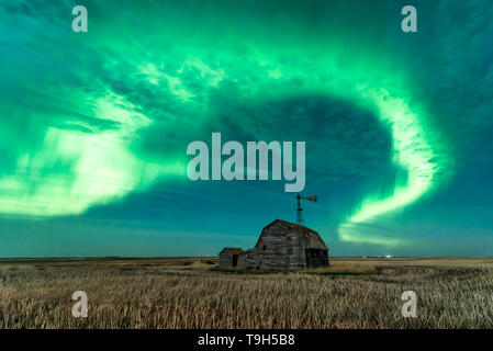 Strudel der helle Polarlichter über vintage Scheune, Behälter, Windmühle und Stoppel in Saskatchewan, Kanada Stockfoto