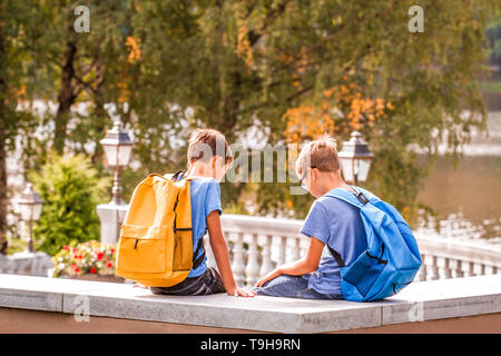 Zwei Kinder nach der Schule, sitzt auf der Bank und Sprechen Stockfoto