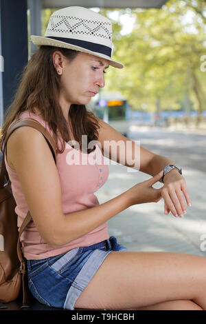 Frau auf ihre Uhr am Busbahnhof auf der Suche Stockfoto