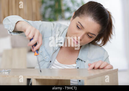 Junge Frau mit Schrauben und Möbelteile Stockfoto