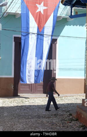 Ein Mann in einem Cowboyhut Spaziergänge Vergangenheit eine kubanische Flagge in Trinidad, Kuba Stockfoto