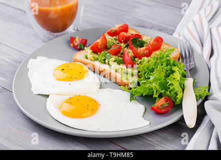 Frühstück. Spiegelei, Salat und ein gegrilltes avocado Sandwich auf grauem Hintergrund. Stockfoto
