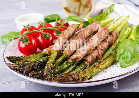 Gegrillter grüner Spargel mit Speck auf hölzernen Tisch gewickelt. Stockfoto