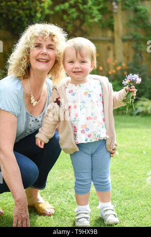 Kleinkind Mädchen von zwei und halb Jahren posie Pflücken von Blumen aus dem Garten mit ihrer Großmutter Foto aufgenommen von Simon Dack Stockfoto