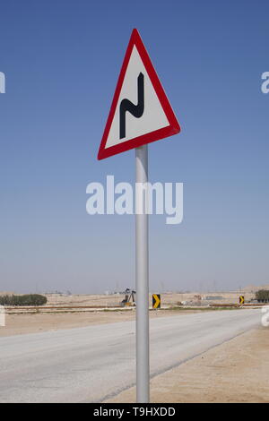 Schild auf einer einsamen Straße, biegt vor, Königreich Bahrain Stockfoto