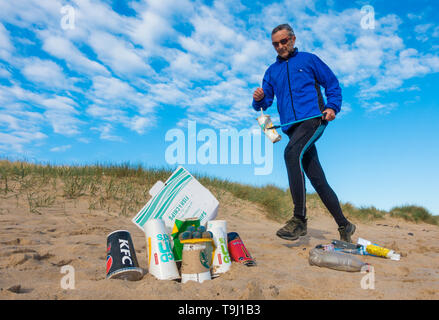 Seaton Carew, County Durham, UK. 19. Mai 2019. UK Wetter: Ein herrlicher Morgen für Plogging. Ein Jogger sammelt Müll auf seinen Morgen laufen durch die Dünen bei Seaton Carew an der nordöstlichen Küste von England. Plogging (Abholung Wurf beim Joggen) ist eine Skandinavische lifestyle Trend wo Jogger Abholung Müll/Kunststoff, wie sie laufen. Credit: Alan Dawson/Alamy leben Nachrichten Stockfoto