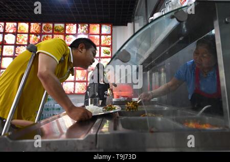 (190519) - Peking, 19. Mai 2019 (Xinhua) - Lin Fushen (1. L) nimmt seine Mahlzeit in einem Restaurant in ein Ölgemälde creative Industrial Park in Lichuan County, der ostchinesischen Provinz Jiangxi, 16. Mai 2019. Lin Fusheng, ein Dorfbewohner aus Hualian Dorf Huashan County im Lichuan County, litt unter körperlicher Behinderung aufgrund von Kinderlähmung. Trotz, dass Lin stecken mit seinem Traum von einem Maler. Wie Lichuan County schnelle Entwicklung der Ölmalerei Industrie in 2013 erlebt, Lin zurück in seine Heimatstadt und wuchs als professioneller Maler mit Hilfe der lokalen Regierung. Stockfoto