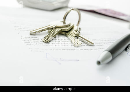 Hausschlüssel und Geld auf einer unterzeichneten Vertrag von Haus Verkauf. Fokus auf Tasten. Stockfoto