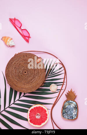 Sommer Zubehör auf der rosa Hintergrund. Kreative Komposition mit runde Tasche, Palm Leaf und andere Stockfoto