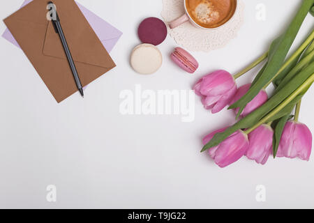 Schöne rosa Tulpen, Tasse Kaffee und macarons auf dem weißen Tabelle, Ansicht von oben Stockfoto