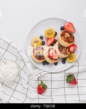 Hüttenkäse pankeas mit Beeren auf dem weißen Teller Draufsicht Stockfoto