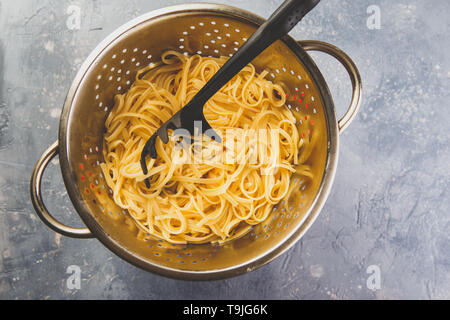 Italienische Pasta linguine in einem Metall Sieb auf grauem Hintergrund. Ansicht von oben. Stockfoto