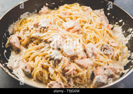 Italienische Pasta Linguine mit Lachs in Sahnesoße in der Pfanne Stockfoto