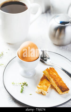 Weich gekochte Eier zum Frühstück mit Toast und Kaffee Tasse im Hintergrund Stockfoto