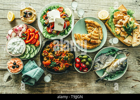 Auswahl an traditionellen griechischen Essen - Salat, Meze, Kuchen, Fisch, Tzatziki, dolma auf Holz Hintergrund Stockfoto