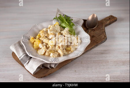 Bacalhau com natas Portugiesische Küche traditionelle Portugal Teller gebackener Kabeljau mit Kartoffeln, Zwiebeln und Sahne in weißem Porzellan Teller Schneidbrett auf Stockfoto