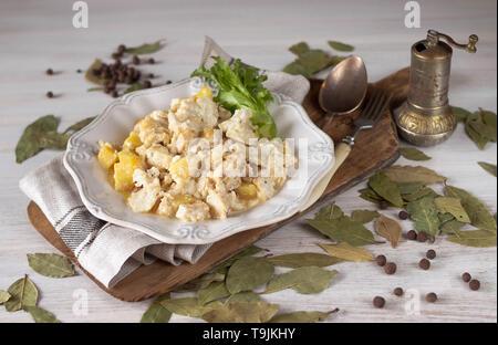 Bacalhau com natas Portugiesische Küche traditionelle Portugal Teller gebackener Kabeljau mit Kartoffeln, Zwiebeln und Sahne in weißem Porzellan Teller Schneidbrett auf Stockfoto