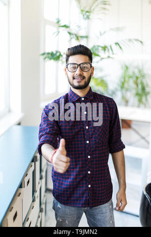 Stattliche Hispanic Mann arbeiten mit Computer und Schreiben auf ein Papier zufrieden mit Lächeln tun ok Zeichen, Daumen hoch, mit den Fingern, ausgezeichnete Zeichen Stockfoto