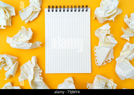 Notepad und zerknittertes Blatt Papier auf einem gelben Hintergrund. Stockfoto