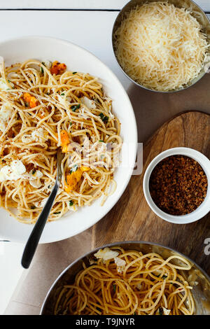 Schnelle und leckere italienische Pasta Spaghetti mit Spiegelei, pangrattato und geriebenem Parmesan auf weiße Platte auf weißem Hintergrund der Ansicht von oben Stockfoto