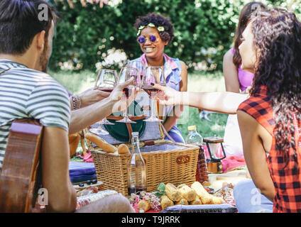 Gruppe der glücklichen Freunde jubeln Gläser Rotwein bei der Pic-nic-Grill im Garten - Junge Leute Spaß an einem Wochenende Tag Stockfoto