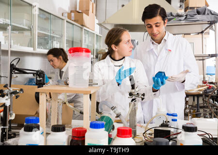 Portrait von Studenten die Prüfung chemischer Substanzen in Glas lab Kolben und Diskutieren bei der Durchführung von Experimenten im Labor der Universität Stockfoto