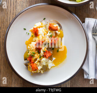 Ember - gebackene Kartoffel mit würzigen Wurst, Pastete und Eier, an Platte im Cafe Stockfoto