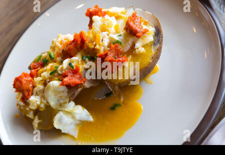 Ember - gebackene Kartoffel mit würzigen Wurst, Pastete und Eier, an Platte im Cafe Stockfoto