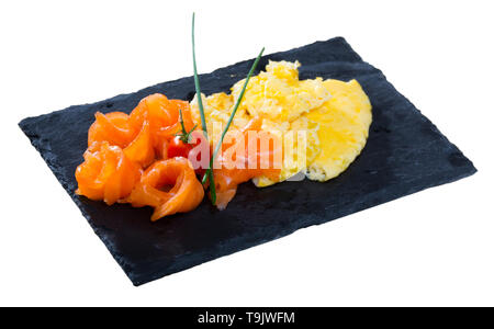 Omelette mit Lachs mit frischem Schnittlauch und Cherry Tomaten auf schwarzem Schiefer Board eingerichtet. Auf weissem Hintergrund Stockfoto