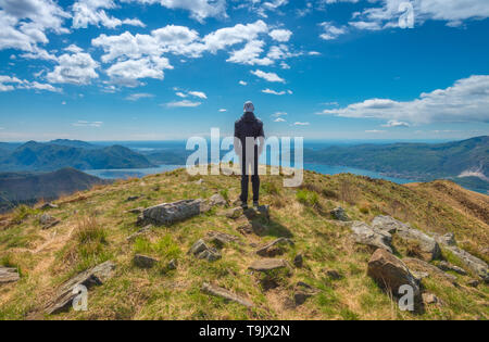 Einsamer Mann, einsame männliche Wanderer sieht am Lago Maggiore vom Gipfel des nahe gelegenen Berg. Gipfel, Einsamkeit auf der Oberseite, Wanderer auf der Spur. Stockfoto