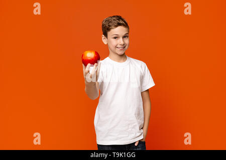 Positive kleiner Junge mit frischen roten Apfel auf der Kamera Stockfoto