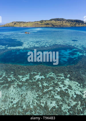 Aus der Vogelperspektive, einem idyllischen tropischen Insel ist durch ein gesundes Korallenriff im Komodo National Park, Indonesia umgeben. Stockfoto