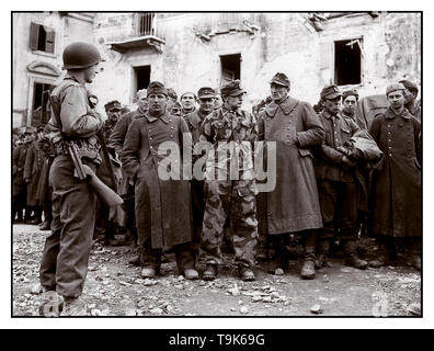 WW2 Archiv deutsche Armee Gefangenen des Zweiten Weltkriegs höchst heterogenen Gruppe von uniformierten Wehrmacht deutsche Armee Gefangenen durch einen jungen amerikanischen GI Soldat an Anzio Italien 1944 bewacht Stockfoto