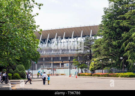 Nur wenige Menschen sind zu Fuß auf ein Quadrat um Baustelle des neuen National Stadium in Tokio. Japan bereitet sich auf neue Olympische Spiele. Stockfoto