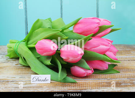 Danke (Vielen Dank, dass Sie sich in Deutscher Sprache) Karte mit Bündel von rosa Tulpen auf Holz- Oberfläche Stockfoto