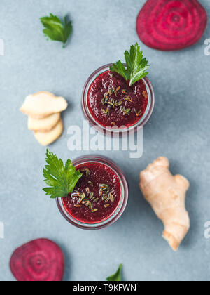 Frische rote Bete und Ingwer Wurzel Smoothie. Rote-bete-Smoothie in Glas Glas auf grau Tabelle. Flache Freiheitsgrad. Kopieren Sie Platz für Text. Sauber essen und detox Konzept, Rezept Idee. Top View oder flach. Stockfoto