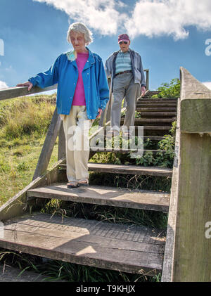 90 Jahre alter Mann nimmt seine Frau, die einen schweren Sehverlust auf dem Land in Wiltshire, in der Natur und weg von Ihrem Haus zu erhalten. Stockfoto